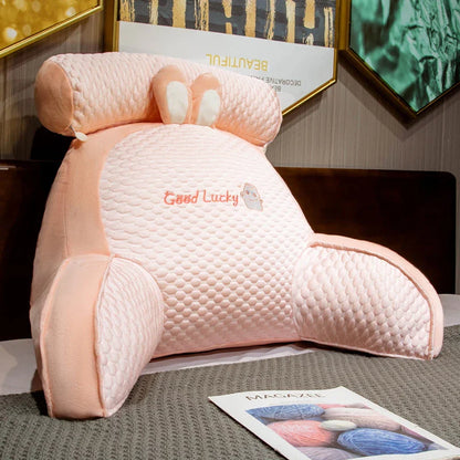 Pink plush toy with 'Good Lucky' text on a surface with a magazine underneath.