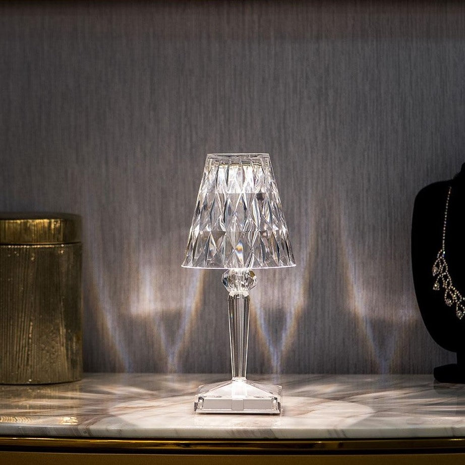 Small glass table lamp on a marble surface with a textured wall background