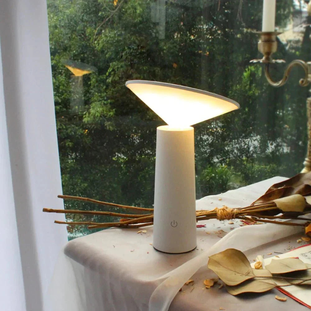 White lamp on a surface with a window in the background