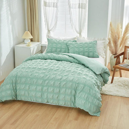 Teal textured comforter set on a bed in a bright bedroom with light wood flooring.